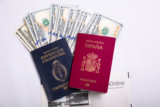 CASH, PASSPORT FROM SPAIN AND PASSPORT FROM ARGENTINA. WHITE BACKGROUND.