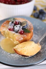 Tasty vanilla fondant with white chocolate and berries on table, closeup