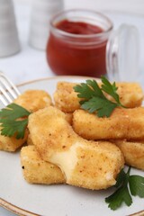 Plate with tasty fried mozzarella sticks and parsley on table, closeup