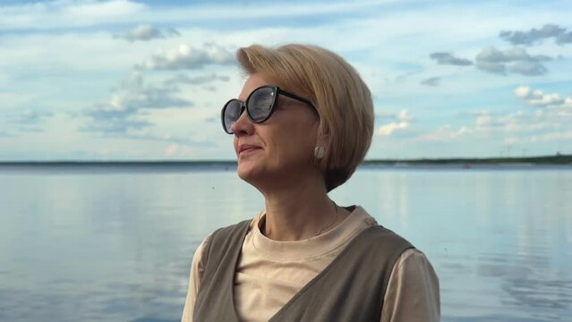 portrait of a beautiful elderly, adult woman in nature near the water sunny summer weather