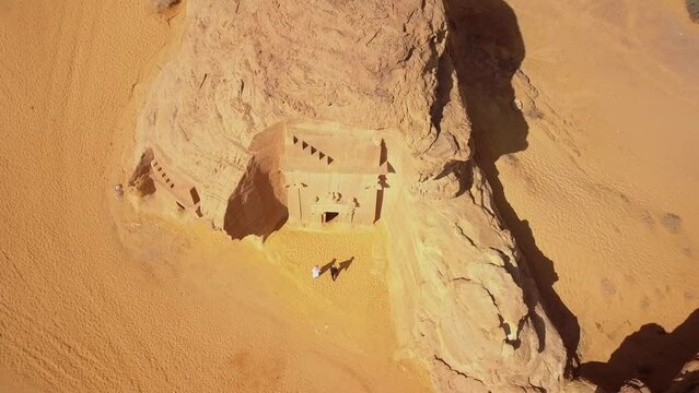 Saudi Arabia top down aerial view of a desert landscape in Al Ula with carved sandstone with temples and tombs with an european woman and saudi person visiting
