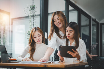 Three women analyzing documents while sitting on a table in office. Woman executives at work in office discussing some paperwork..