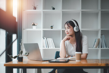 Pretty young woman listening to music with laptop computer and relaxing while sitting on chair at home.