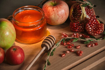 Traditional Jewish new year food card. Red and green apples, pomegranate and honey on wooden background. Happy Rosh Hashanah concept.