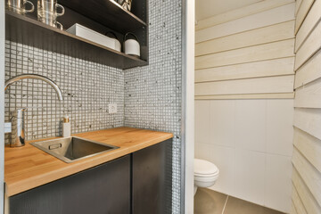 a kitchen with wood counter tops and white tiles on the wall behind it is a sink, fauced by an open shelf