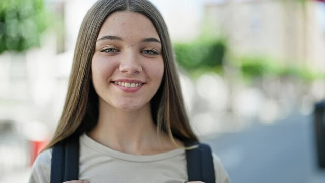 Young beautiful girl student smiling confident wearing backpack at street