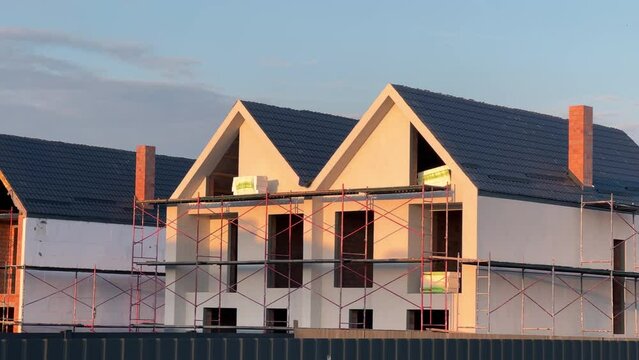 Duplexes under construction with scaffolding in the suburbs at summer sunset