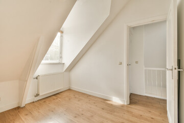 a room with wood flooring and an attic style window in the room has white walls, wooden floors and a rad door