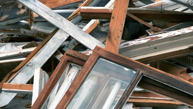 Old wooden windows lie in a pile near the building after being replaced with modern double-glazed windows