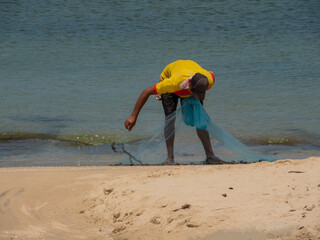 a man fishing on the beach by casting nets along the coast. fisherman are casting a net to catch...