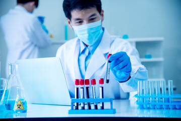 Scientist man holding sample blood test tube in science laboratory. Doctor clinic healthcare...