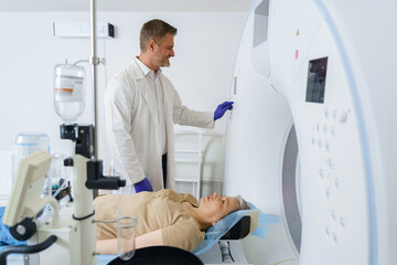 Doctor pushing button on panel to start mri scan procedure for female patient. High quality photo