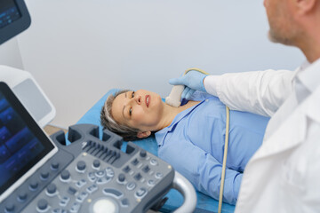 Adult woman having thyroid exam with ultrasound at doctor's office. Healthcare concept