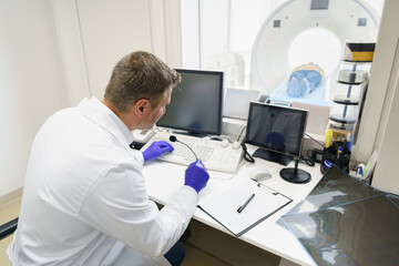 Radiologist controls MRI or CT Scan with patient undergoing procedure. High Tech medical equipment