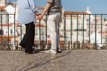 Close up of couple in love holding hands while walking on old city street. High quality photo