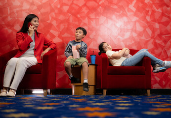 Mother and children watching movie in cinema, sitting on red armchair