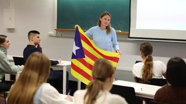 Geography lesson in school class - teacher talks about Catalonia, holding a flag in his hands. High quality 4k footage