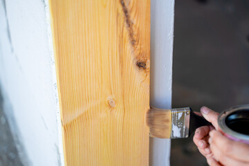 A woman's hand opens a wooden board with varnish, close-up. Lacquered pine door frame