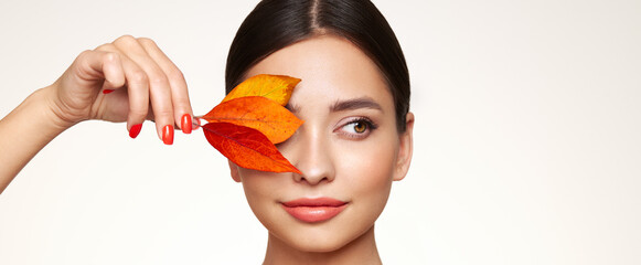 Portrait of beautiful young woman with autumn leafs. Healthy clean fresh skin natural make up beauty eyes and red nails