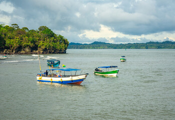 Fototapeta na wymiar Boats on the beach floating in the sea of ​​Bahía Málaga, surrounded by mountains and trees in Buenaventura, Valle del Cauca, Colombia