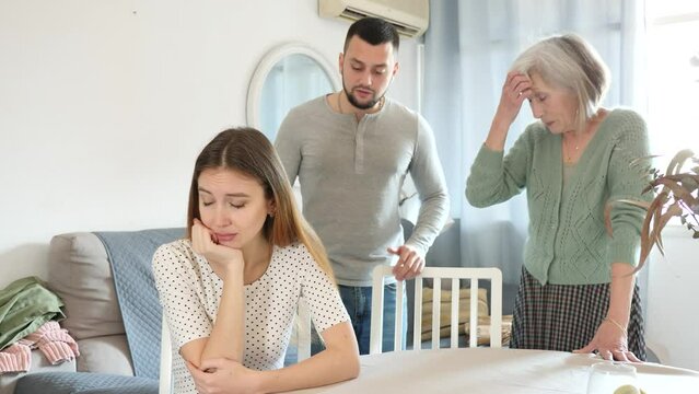 Upset woman sitting at table while man and woman arguing behind her back. High quality 4k footage