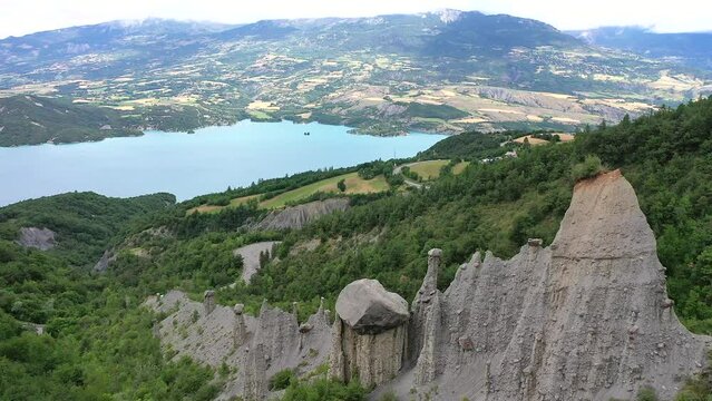 Drone shot, drone video, drone flight, aerial view, flight over the Demoiselles Coiffees, fairy chimneys, pillars. geological phenomenon, far view, lake, forest, Provence Alps Cote d'Azur, France