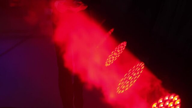 Special smoke effect. A man walks along the smoke. Lighting stage equipment. The lamps shine red.