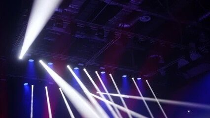Lighting equipment suspended from the ceiling of a large stadium. Static picture. White, blue, red lights.