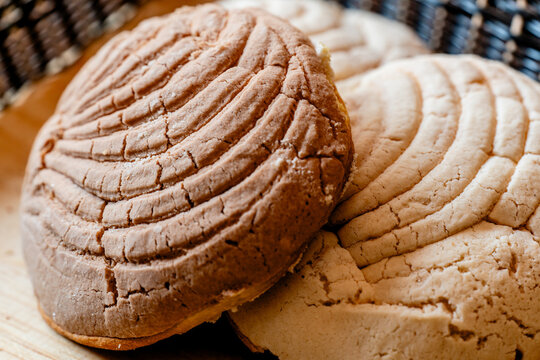 typical mexican bread - chocolate concha on top of two vanilla conchas side view