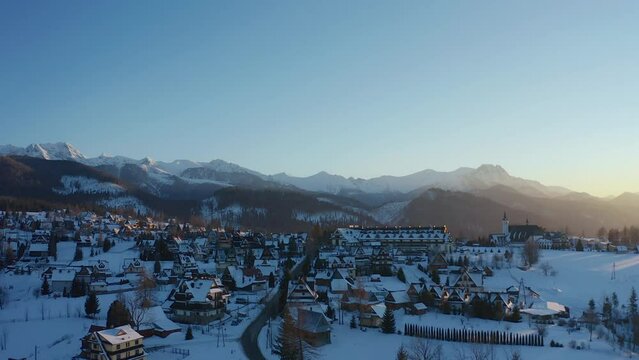 Stunning drone aerial shot of a a traditional town during golden hour with mountains backdrop