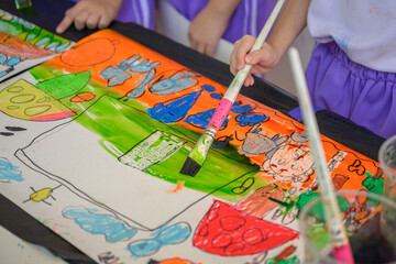 Close-up shot of hands of children drawing and painting water or crayons on paper of their own...