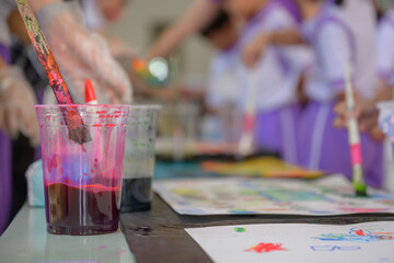 Close-up shot of hands of children drawing and painting water or crayons on paper of their own creative creativity in bright colors in kindergarten class in school.