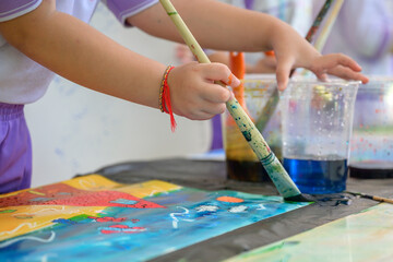 Children draw and paint water or crayons on the colorful drawing paper of their own creativity in the kindergarten class at the school.