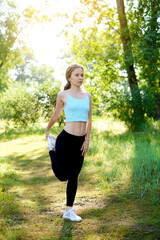 Young woman doing exercises, stretching before sport training on a park. Summer sunny day outdoor for active life