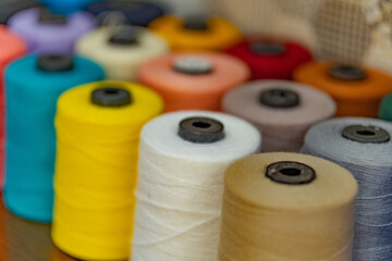 Colorful yarn on spool, tube, cotton, wool, linen thread. Colorful thread spool background, close-up. Multi Colored threads for sewing and needlework