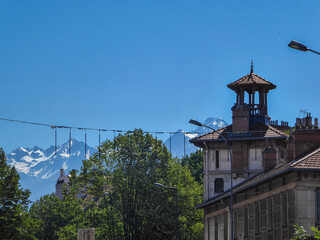 Scenic view of architectural significant building with snow capped mountain peaks in the background seen in Grenoble, Auvergne-Rhone-Alpes region, France, Europe. Luxury building in the French Alps