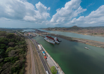 Boat passing Pedro Miguel locks in Panama, famous channel shortcut in central America. Visible ships and channels with locks. Drone view on a cloudy but sunny day in spring.