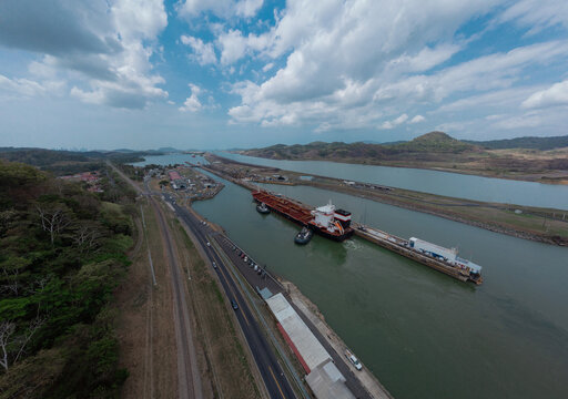 Boat passing Pedro Miguel locks in Panama, famous channel shortcut in central America. Visible ships and channels with locks. Drone view on a cloudy but sunny day in spring.