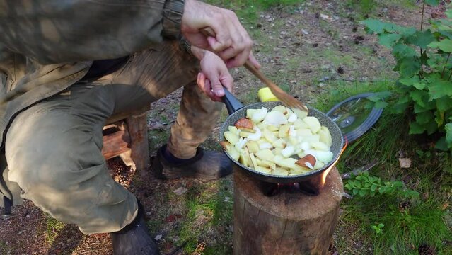 Cooking potato on a finnish candle. Roasting potatoes in a frying pan over an open fire