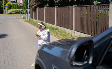 Girl with headphones and cellphone crossing the road, not looking at car let