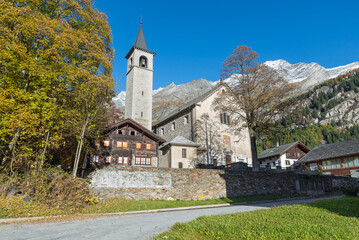Fototapeta na wymiar Picturesque old mountain church in autumn. Traditional alpine village of Macugnaga, Piedmont, Italy. European alps. Parish Church of Santa Maria Assunta and San Giuseppe