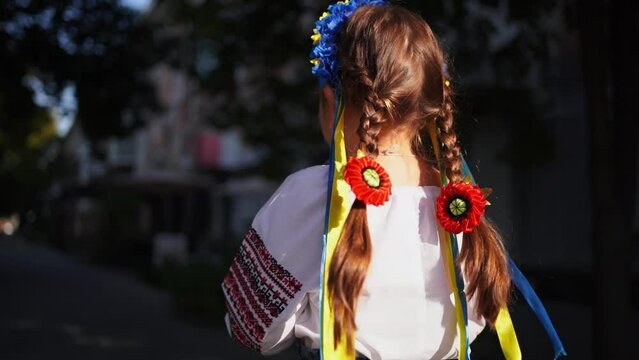 Child girl in Ukrainian traditional clothes and flower wreath is praying outdoors in a sunlight. traditional culture of Ukraine, Slavic child