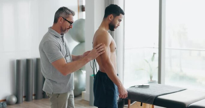 Physiotherapist with electrical muscle stimulator for rehabilitation, recovery and health performance. Healthcare, physical therapy and man with machine to test muscles strength for patient wellness