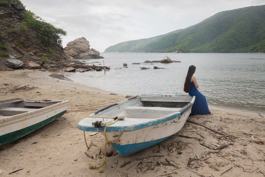 girl in blue dress sitting on fishing boat on the beach in Colombia