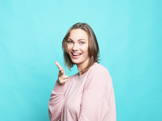 Portrait of cheerful young woman feels joyful and laughing isolated over blue background