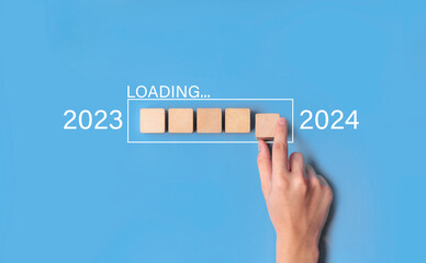 hand putting wood block for loading year 2023 to 2024. start and countdown concept.