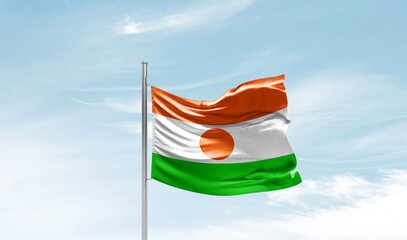 Niger national flag waving in beautiful sky. The symbol of the state on wavy silk fabric. - obrazy, fototapety, plakaty