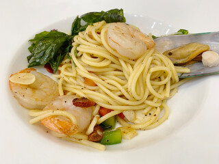 Spaghetti with seafood on a white plate, close-up.