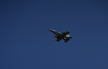Bucharest International Air Show. F16 military fighter airplane flying against dark blue sky. Military aviation aircrafts and war missiles industry.