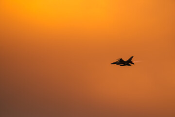 Fototapeta na wymiar Bucharest International Air Show. F16 military fighter airplane flying against sunset sky. Military aviation aircrafts and war missiles industry.